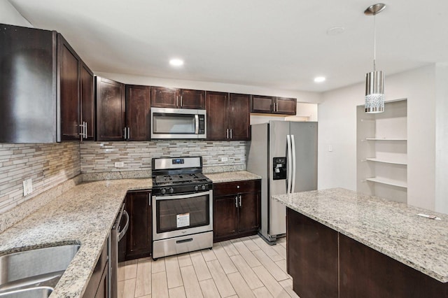 kitchen with stainless steel appliances, tasteful backsplash, light stone countertops, dark brown cabinetry, and light wood-style flooring