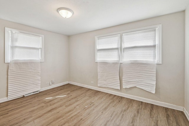 spare room featuring wood finished floors, a healthy amount of sunlight, and baseboards