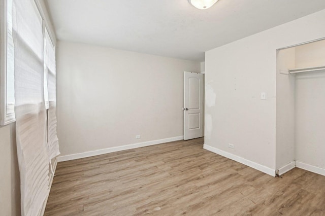 unfurnished bedroom featuring wood finished floors, a closet, and baseboards