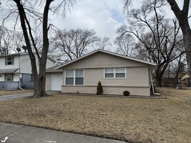 view of front of house featuring brick siding, a front lawn, an attached garage, and driveway