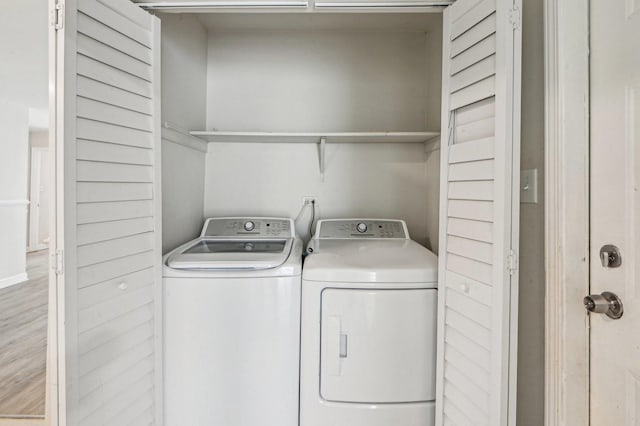 washroom with independent washer and dryer, wood finished floors, and laundry area