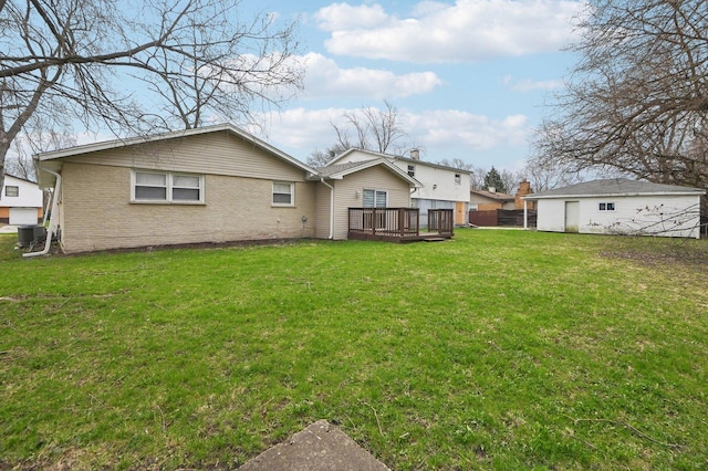 rear view of property featuring fence, brick siding, a yard, and a deck