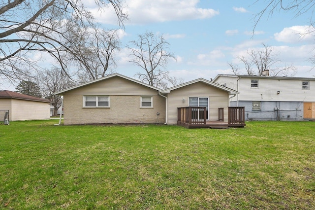 rear view of property with brick siding, a lawn, and a deck