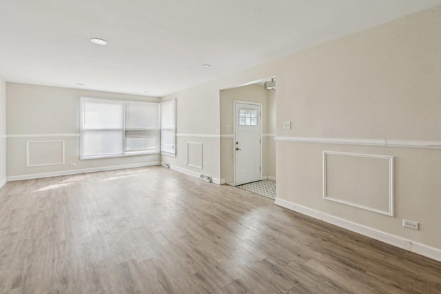 spare room featuring baseboards, wood finished floors, and visible vents
