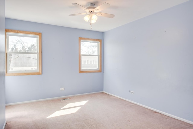 carpeted empty room with visible vents, baseboards, and a ceiling fan