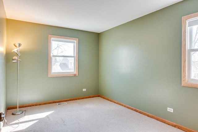 carpeted spare room featuring visible vents and baseboards