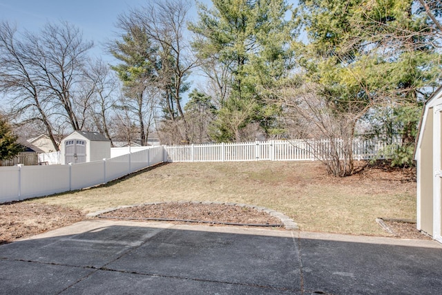 view of yard featuring an outdoor structure, a fenced backyard, and a shed