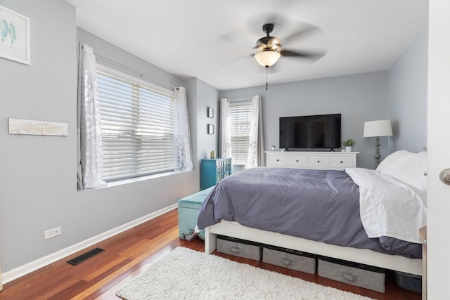 bedroom featuring ceiling fan, visible vents, baseboards, and wood finished floors