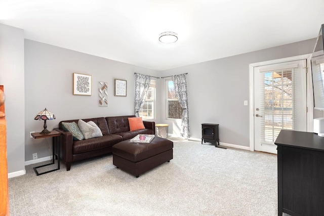 living room featuring light carpet, a wood stove, and baseboards