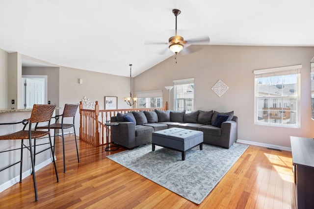 living room featuring ceiling fan with notable chandelier, light wood-style flooring, baseboards, and lofted ceiling