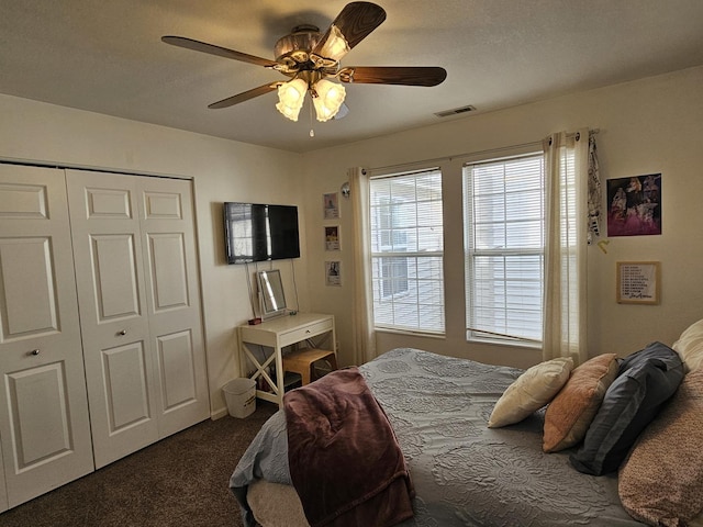 bedroom with a closet, visible vents, a ceiling fan, and dark colored carpet