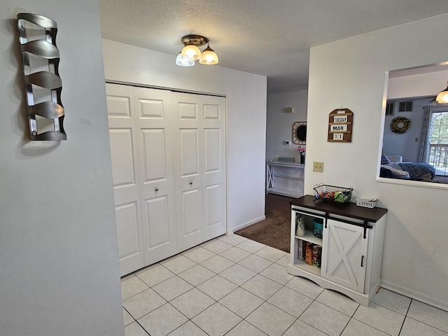 entrance foyer with light tile patterned floors, baseboards, and a textured ceiling