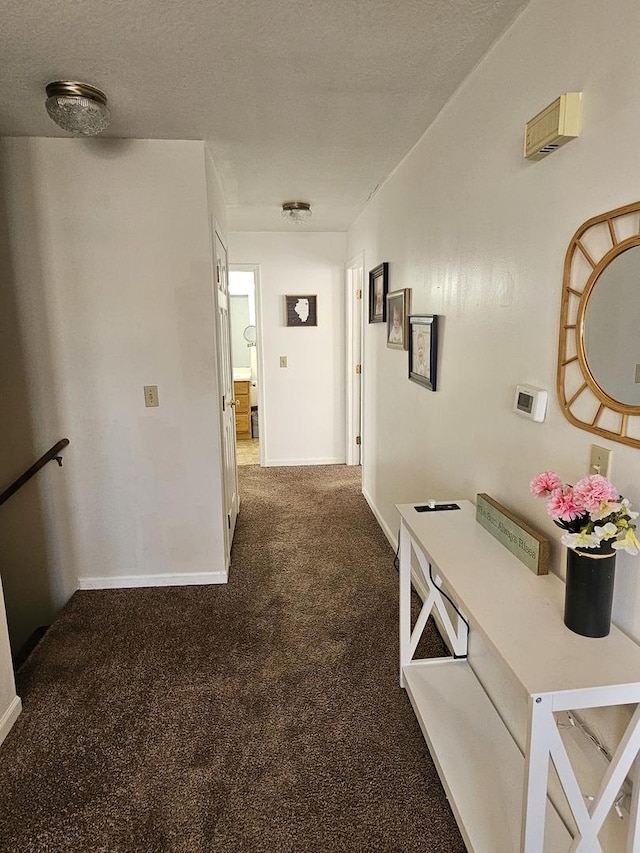 hallway featuring carpet flooring, a textured ceiling, and baseboards