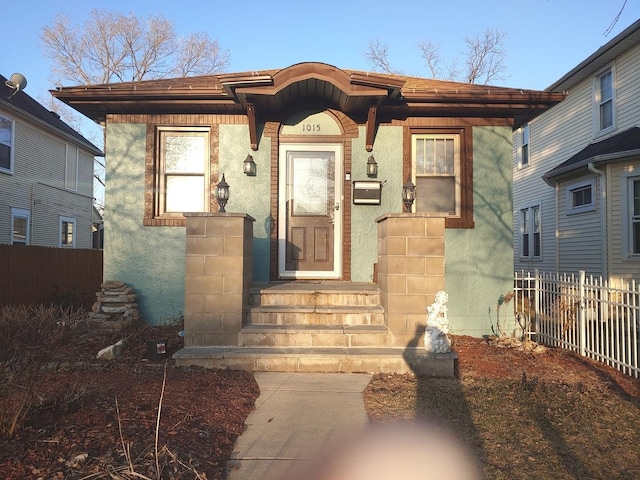 view of front facade featuring stucco siding and fence