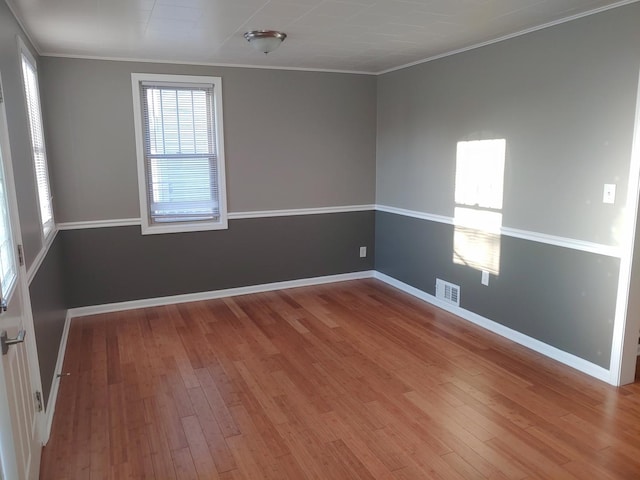 spare room with visible vents, baseboards, hardwood / wood-style floors, and ornamental molding