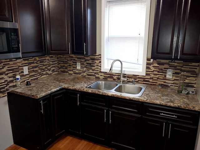 kitchen with a sink, stainless steel microwave, tasteful backsplash, and a wealth of natural light