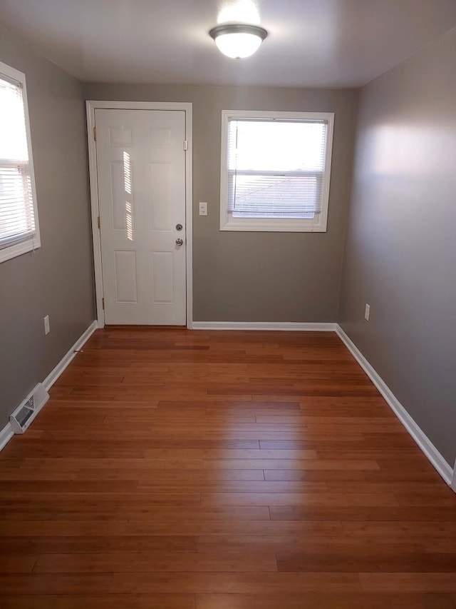 foyer entrance with visible vents, baseboards, and wood finished floors