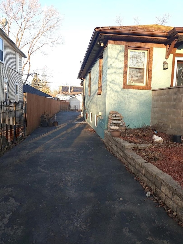 view of property exterior with stucco siding and fence