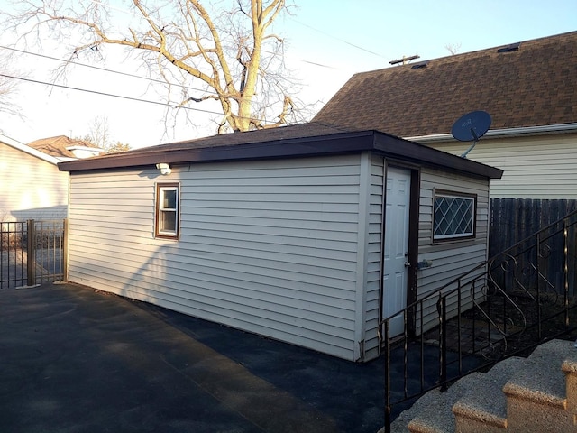 exterior space with an outdoor structure, roof with shingles, and fence