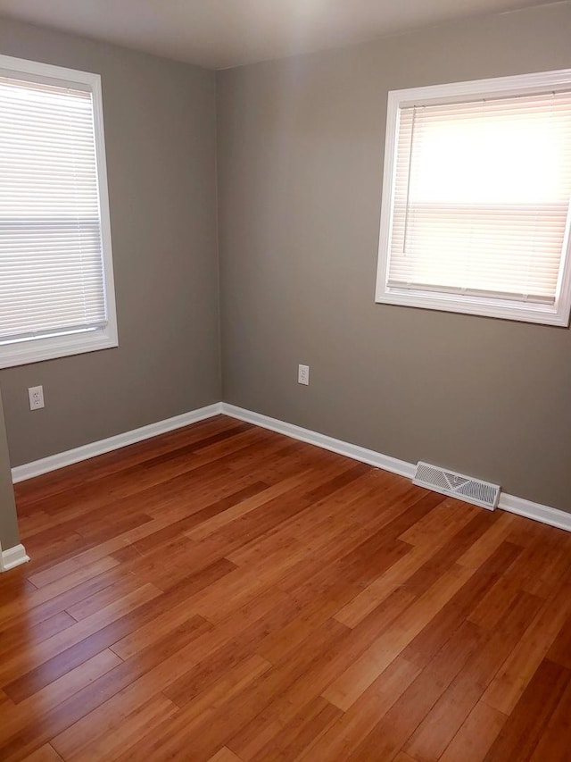 unfurnished room with baseboards, visible vents, and light wood-type flooring