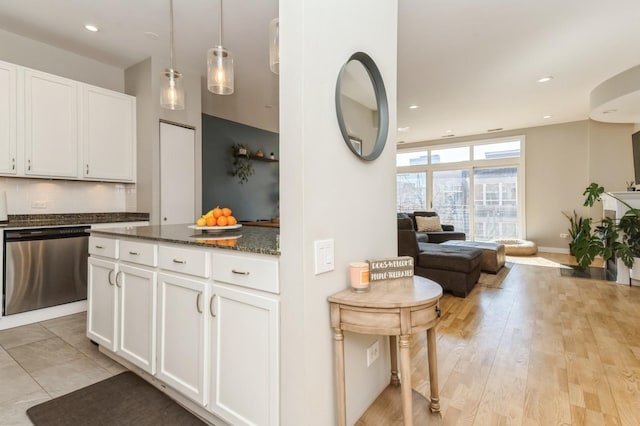 kitchen with open floor plan, dark stone countertops, dishwasher, and white cabinetry