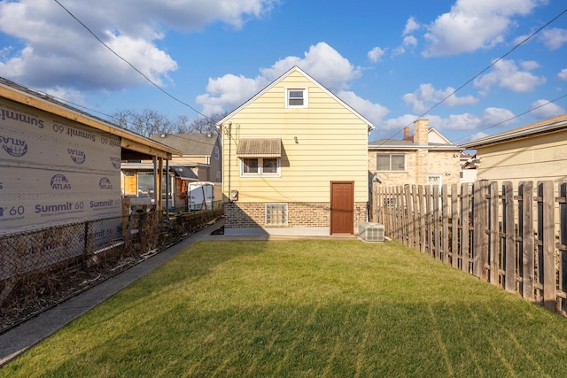 rear view of property featuring a lawn and a fenced backyard