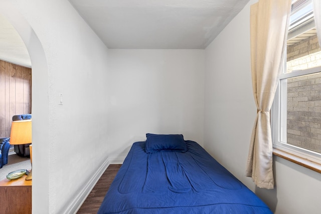 bedroom featuring arched walkways, baseboards, and wood finished floors