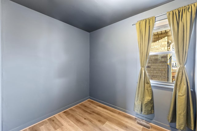 empty room with light wood-type flooring, visible vents, and baseboards