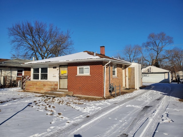 exterior space with an outdoor structure, brick siding, a detached garage, and a chimney