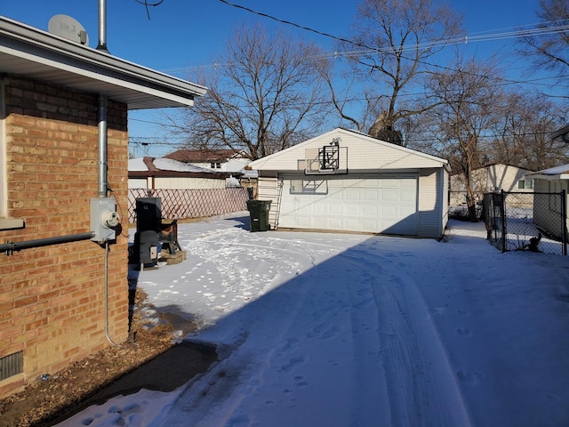 yard covered in snow with an outdoor structure, fence, and a garage