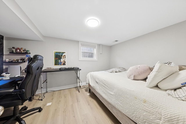 bedroom with baseboards, visible vents, and light wood finished floors