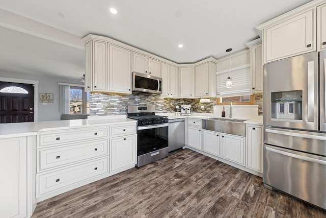 kitchen with a sink, backsplash, dark wood finished floors, stainless steel appliances, and light countertops