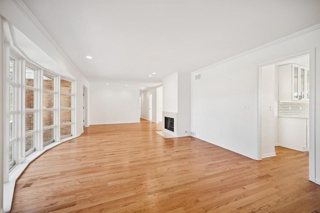 unfurnished living room featuring a fireplace with flush hearth, light wood-style flooring, visible vents, and ornamental molding