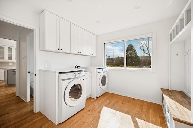 laundry area featuring washer and clothes dryer, cabinet space, light wood-type flooring, and baseboards