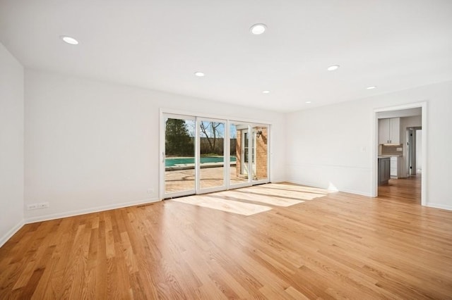 empty room with recessed lighting, light wood-type flooring, and baseboards