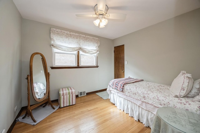 bedroom with ceiling fan, visible vents, baseboards, and wood finished floors