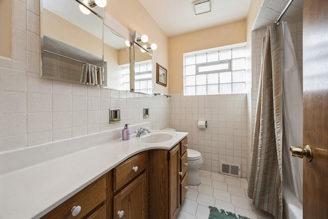 bathroom with vanity, visible vents, tile patterned flooring, tile walls, and toilet