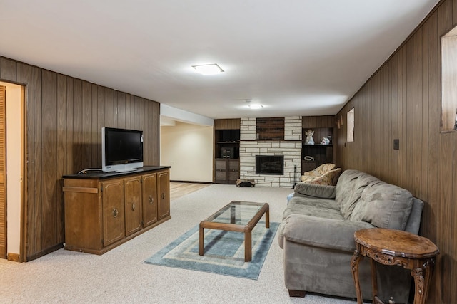 living area featuring light colored carpet, a fireplace, baseboards, and wood walls