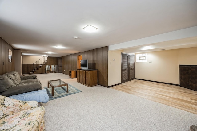 living area with stairs, light wood finished floors, wood walls, and light carpet