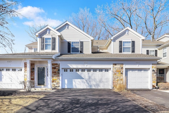 view of front of property with stone siding, driveway, and an attached garage