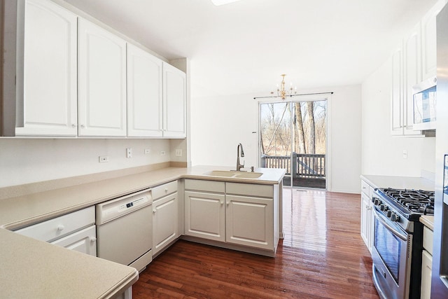 kitchen with dark wood finished floors, dishwasher, a peninsula, gas stove, and a sink