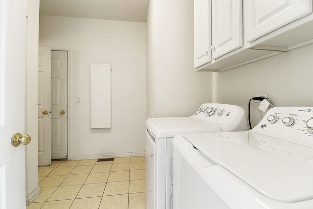 washroom with visible vents, baseboards, washer and clothes dryer, light tile patterned flooring, and cabinet space