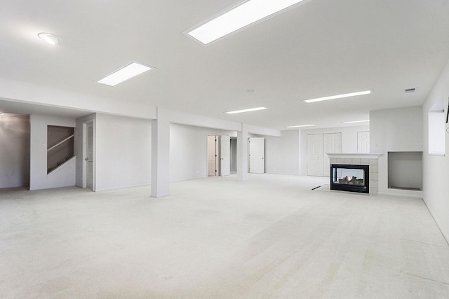 unfurnished living room with visible vents, carpet flooring, and a tiled fireplace