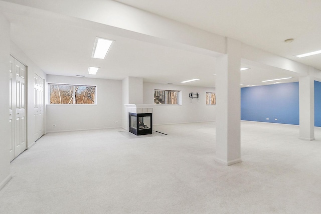 below grade area featuring carpet, baseboards, and a tile fireplace