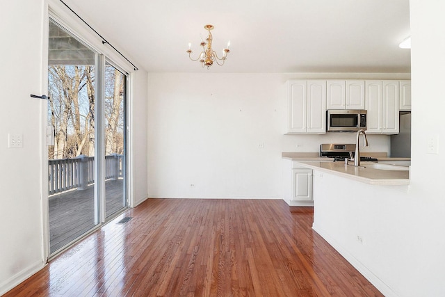 kitchen with white cabinetry, light countertops, wood finished floors, and appliances with stainless steel finishes