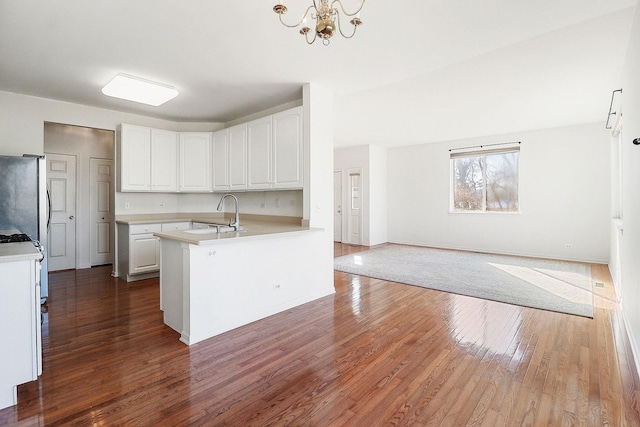 kitchen featuring a sink, light countertops, freestanding refrigerator, white cabinetry, and dark wood-style flooring