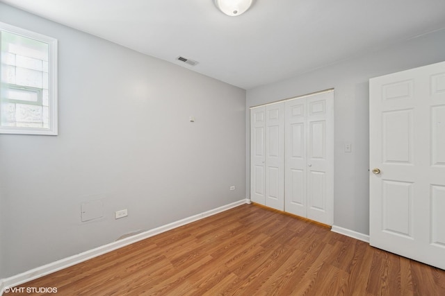 unfurnished bedroom featuring a closet, baseboards, light wood-style floors, and visible vents