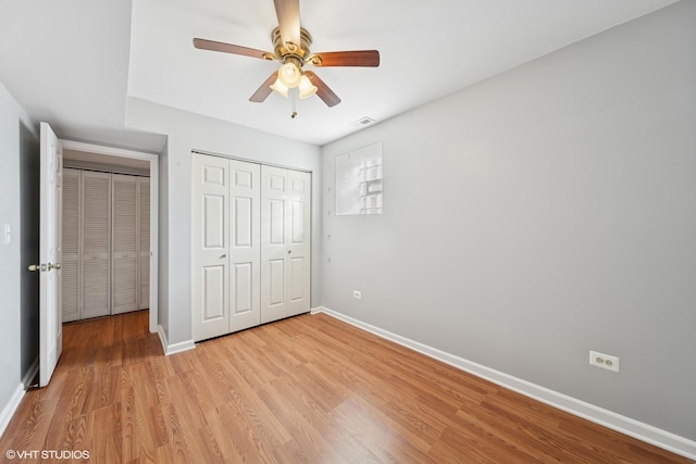 unfurnished bedroom featuring light wood finished floors, visible vents, ceiling fan, baseboards, and a closet