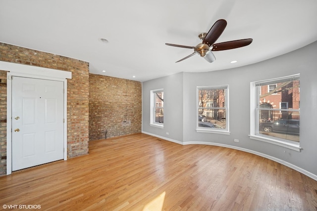 unfurnished room featuring a ceiling fan, wood finished floors, baseboards, brick wall, and recessed lighting