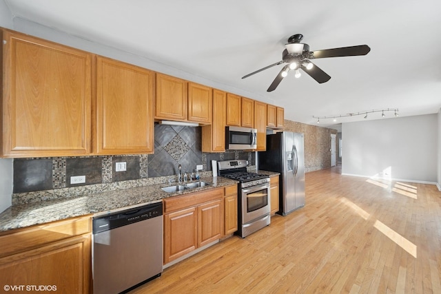 kitchen featuring light wood-type flooring, a sink, tasteful backsplash, appliances with stainless steel finishes, and ceiling fan